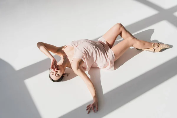 优雅迷人的芭蕾舞演员躺在阳光下躺在地板上 — 图库照片