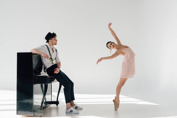 Beautiful musician holding rose and looking at dancing beautiful ballerina
 