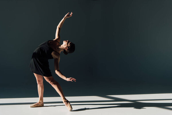 attractive ballerina  dancing in black dress and pointe shoes