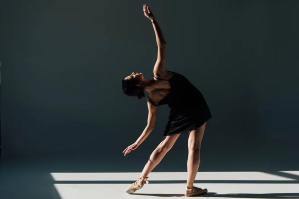优雅的年轻芭蕾舞演员穿着黑色礼服在阳光下跳舞 — 图库照片