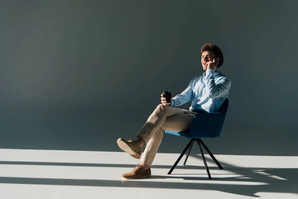 Gülümseyen Güneş Işığı Altında Sandalyede Otururken Smartphone Konuşan Adam — Stok fotoğraf