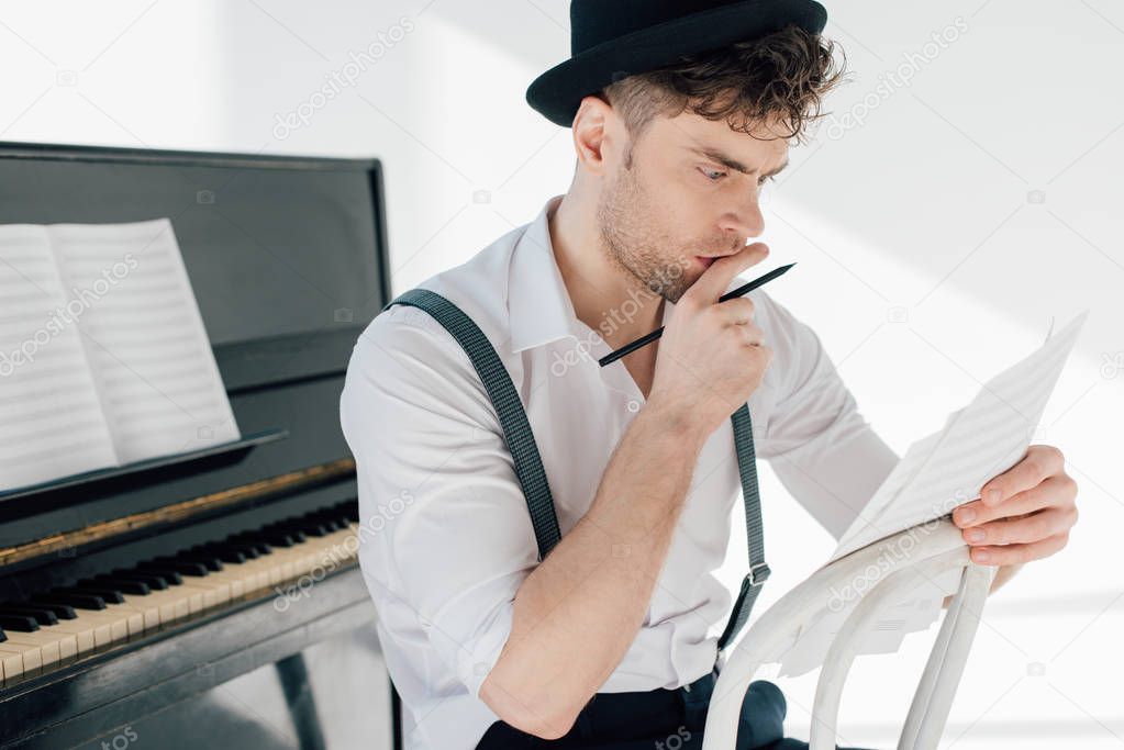 selective focus of thoughtful musician holding music book sheets 