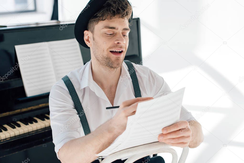 selective focus of cheerful man composing music at home