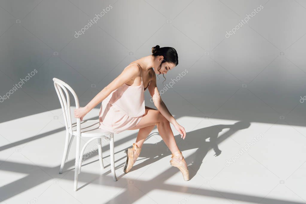 beautiful ballerina sitting on white chair in sunlight