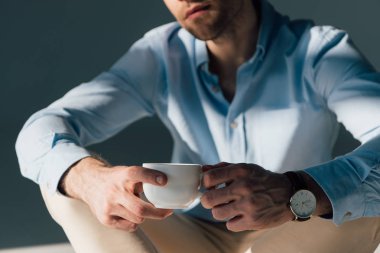 seçici odak kahve fincanı tutan oturan adamın 