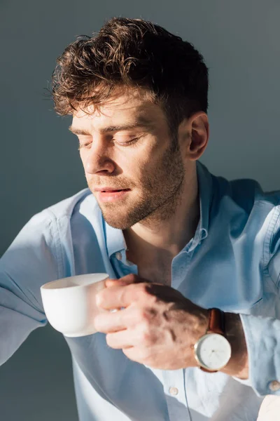 Przystojny Mężczyzna Zamyślony Trzymając Kubek Kawy Siedząc Słońcu — Zdjęcie stockowe