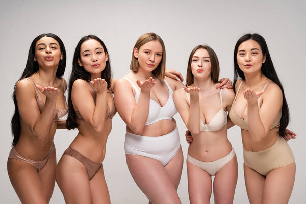 five pretty multicultural girls in lingerie sending air kisses isolated on grey, body positivity concept