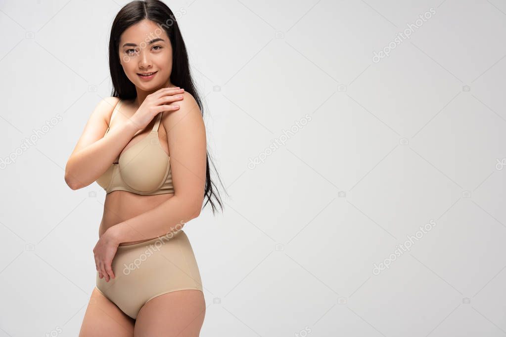 attractive overweight woman looking at camera isolated on grey, body positivity concept