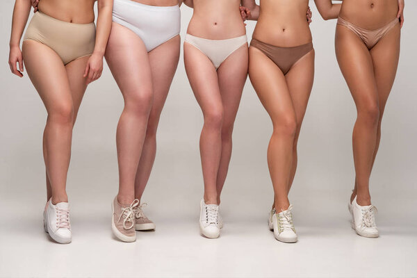 cropped view of five multicultural women in underwear and sneakers, body positivity concept