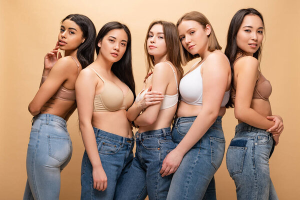 five beautiful multicultural girls posing at camera isolated on beige, body positivity concept