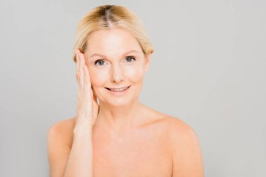 yüzünü dokunaklı ve gri izole kamera seyir çekici ve gülümseyerek Olgun kadın