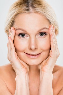 Kameraya bakarak ve gri izole yüzüne dokunmak güzel ve sarışın Olgun kadın 