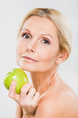 Yeşil olgun elma tutarak ve gri izole kamera bakıyor güzel ve Olgun kadın