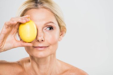 Olgun limon tutarak ve Dış saha üzerinde izole gri arıyorum güzel ve Olgun kadın