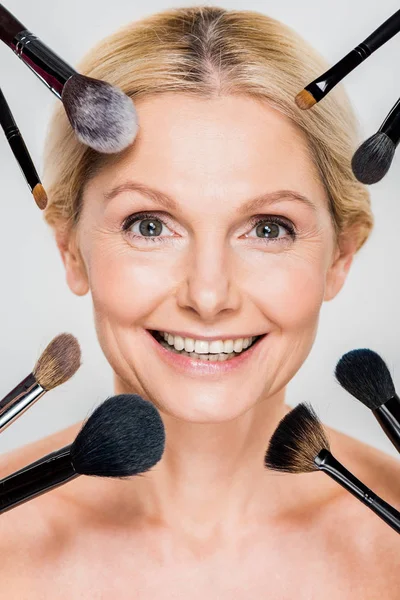 Hermosa Sonriente Mujer Mirando Cámara Con Cepillos Cosméticos Aislados Gris —  Fotos de Stock