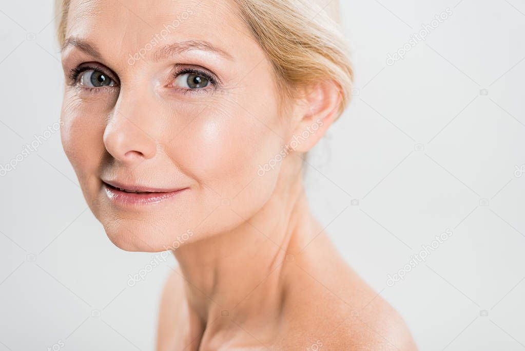 attractive and blonde mature woman looking at camera isolated on grey 