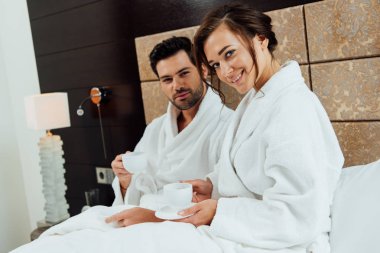 neşeli sakallı adam ve güzel kız yatakta kahve ile bardak tutan