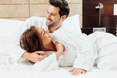 bornoz kucaklama mutlu kız yatakta yatarken neşeli adam 