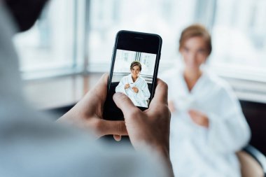 bornoz otelde otururken holding Kupası çekici kız fotoğraf çekici adamın seçici odak 
