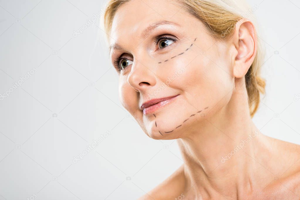 beautiful and middle aged woman with lines on face looking at camera on grey background 
