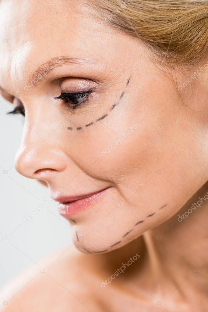 close up of beautiful and middle aged woman with lines on face looking down isolated on white