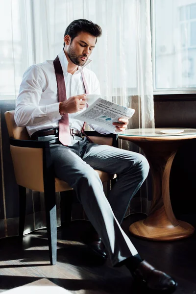 Hombre Guapo Traje Sentado Cerca Mesa Café Mientras Lee Periódico — Foto de Stock