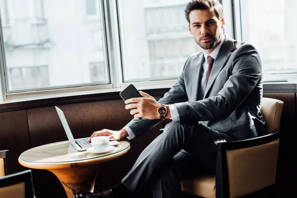 Knappe Bebaarde Zakenman Bedrijf Smartphone Terwijl Het Gebruiken Van Laptop — Stockfoto