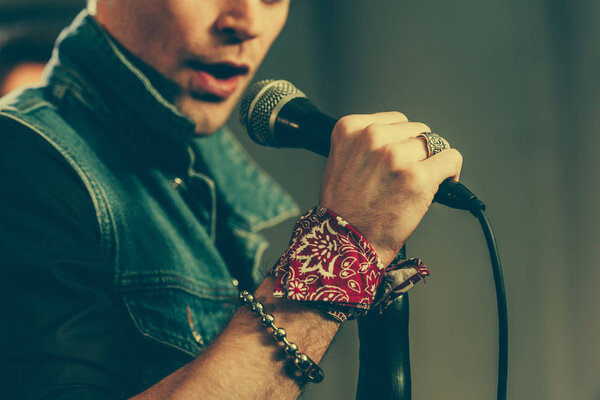 cropped view of stylish man singing in microphone 