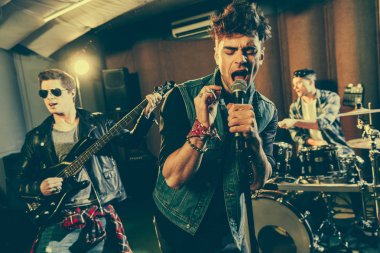 seçici odak mikrofon gitarist güneş gözlüğü ve davulcu yakınındaki şarkı şarkıcı 