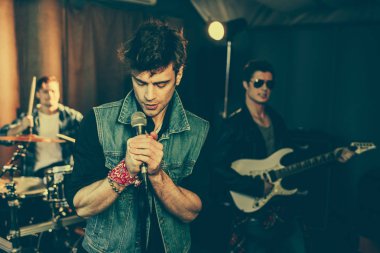 seçici odak şık adam şarkı şarkı mikrofon yakınındaki rock grubu 