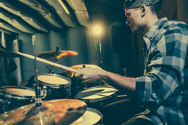 selective focus of drummer holding drum sticks while playing drums 