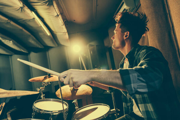 handsome musician holding drum sticks and playing drums