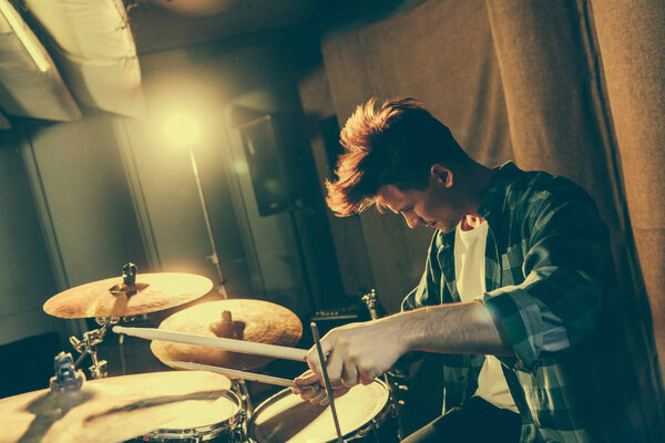 handsome musician holding drum sticks while playing drums
