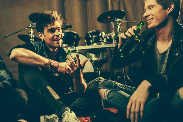 selective focus of cheerful friends talking while holding glass bottles with beer 