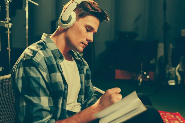 Ernsthafter Junger Komponist Hört Musik Kopfhörer Während Notizbuch Schreibt — Stockfoto