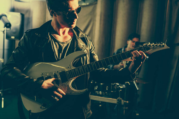 selective focus of man in sunglasses playing elecric guitar