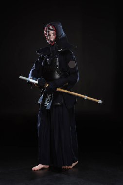 Tam boy görünüm kendo Fighter bambu kılıcı tutan siyah kask içinde