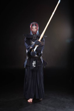 Tam boy görünüm kendo Fighter bambu kılıcı tutan siyah kask içinde