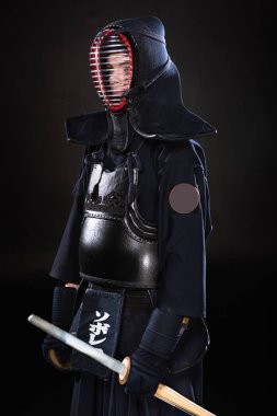Kendo fighter in armor holding bamboo sword on black clipart