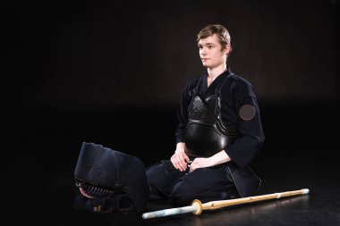 Kendo zırh siyah üzerine oturan kask ve bambu kılıçla genç adam