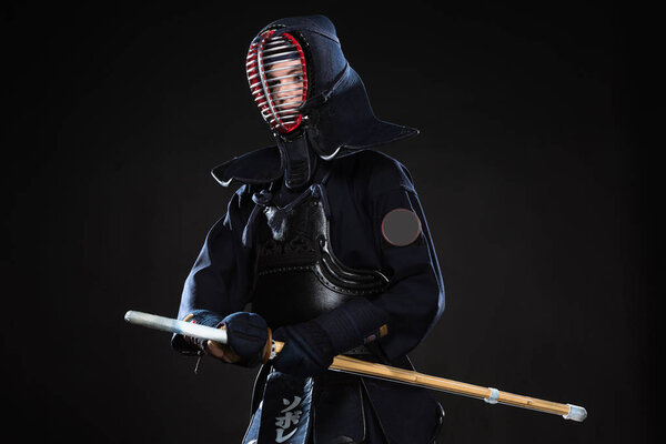 Боец Кендо в шлеме держит бамбуковый меч и смотрит в сторону черного

