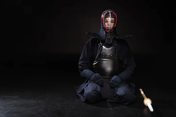 带着竹剑坐在黑色上的头盔的剑道战士 — 图库照片