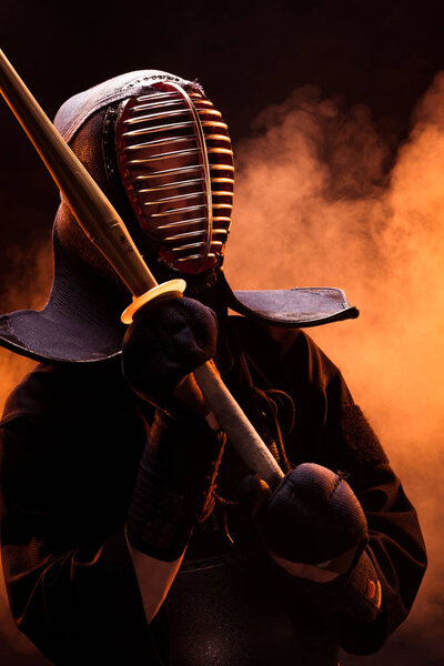 Боец Кендо в доспехах держит бамбуковый меч в дыму
