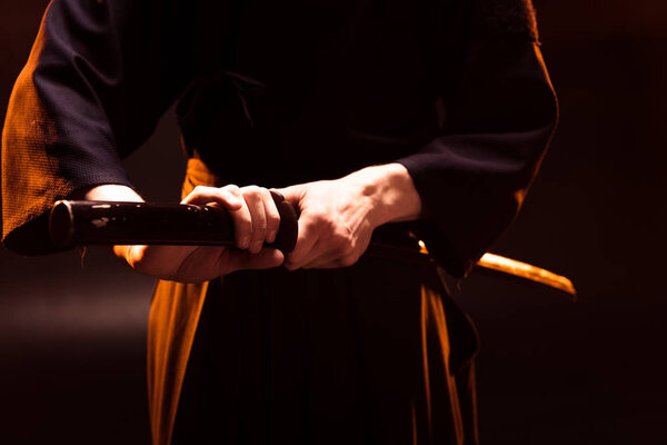 Частичный вид борца кендо с бамбовым мечом на черном
