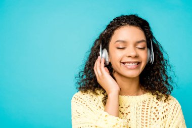 mavi üzerinde izole kapalı gözleri ile kulaklıkta müzik dinleme mutlu kıvırcık Afrikalı Amerikalı kız