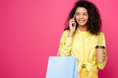 Kırmızı üzerinde izole kağıt fincan tutarak Akıllı Telefonda konuşan alışveriş torbaları ile kıvırcık Afrikalı Amerikan kadın