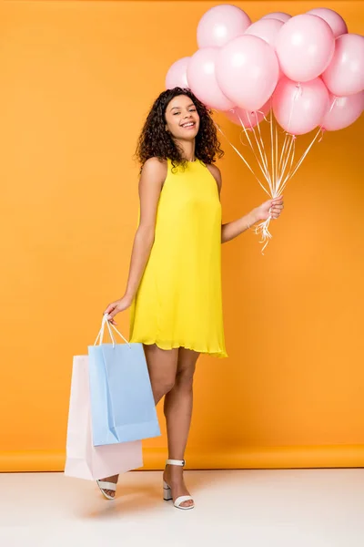 Счастливая Африканская Американка Держит Сумки Покупками Розовые Воздушные Шары Оранжевом — стоковое фото