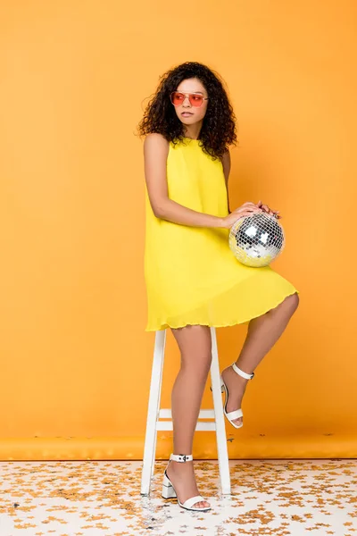 Attractive Curly African American Woman Holding Disco Ball While Sitting — Stock Photo, Image