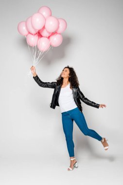 gri pembe Hava balonlar tutan neşeli Afrikalı Amerikalı genç kadın
