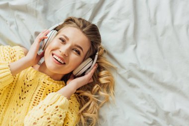 yatak ve kopya alanı ile müzik dinleme yatarken kulaklıklar güzel gülümseyen genç kadın üst görünümü